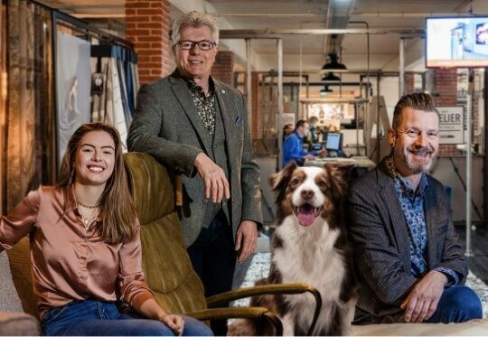 Een drietal werknemers van Poels Wonen & Slapen zitten samen met hondje Joy.